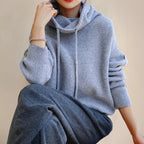 Gray Women's Merino Wool Turtleneck Sweater with Drawstring Hood & Oversized Fit - Seated Pose